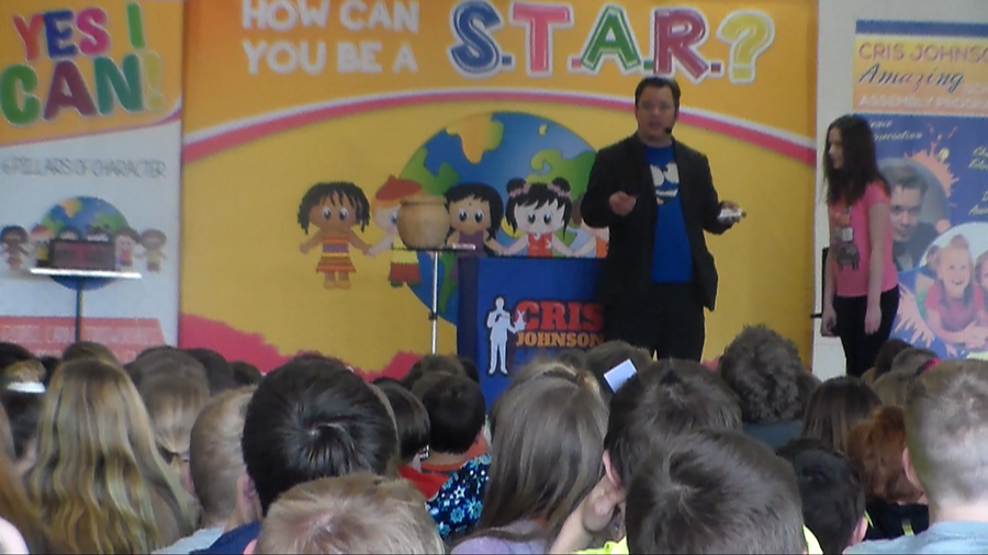 character education school assembly presenter Cris Johnson on a stage with a volunteer