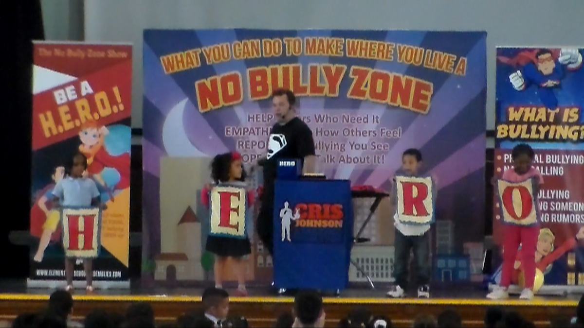 school assembly presenter Cris Johnson at a bully prevention show with 4 volunteers