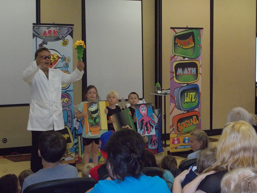 School assembly presenter Cris Johnson with 3 volunteers at a science show